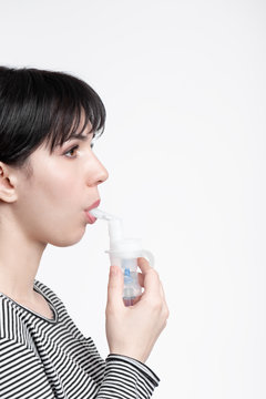 profile picture of brunette woman using inhaler. patient inhale medicine . closeup