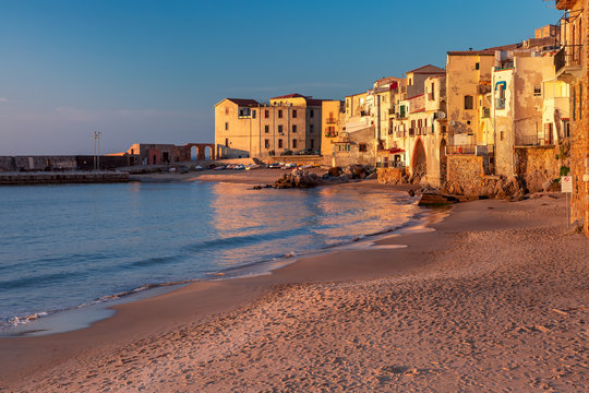 Empty sand beach in old town of coastal city Cefalu at sunset, Sicily, Italy