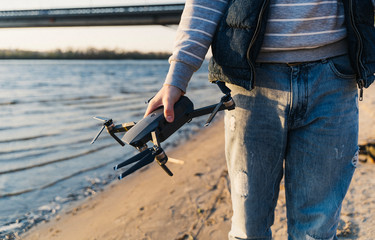 A quadcopter in the hands of a guy on the beach