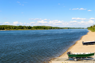 Fototapeta na wymiar Amazing rippling blue river with sandy shore, green trees and boats