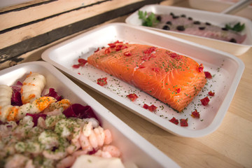Salmone conditeo in vaschetta e altri prodotti ittici sopra un tavolo 
