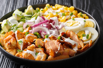 Healthy salad of fried chicken, avocado, corn, onion, eggs seasoned with yogurt close-up in a plate. horizontal