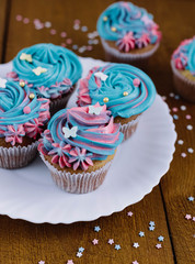 Pink-blue cupcakes in a white plate on a wooden background