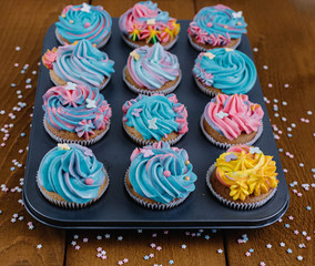 Colored cupcakes on a wooden background in a baking dish