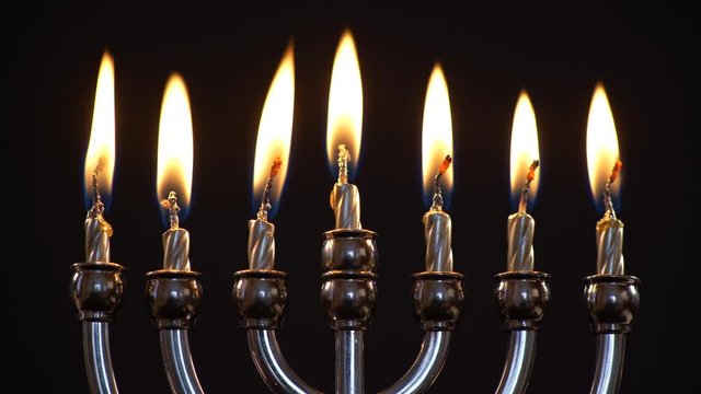 Close up of Menorah With All Candles Burning on Black Background