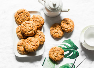 Tea party set table - teapot, teacup, oatmeal nuts cookies on a light background, top view
