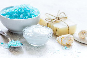 Obraz na płótnie Canvas blue bath salt, body cream and shells for spa on white table background