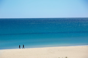 Fototapeta na wymiar spiaggia della Sardegna con sfondo mare e cielo e due persone in lontananza che passeggiano