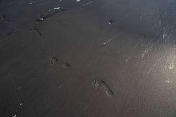 Strand Landschaft schwarzer Sand Meer Fußspuren 
