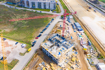 Construction site with cranes. Construction workers are building. Aerial view apartment building construction, cranes on sunset background
