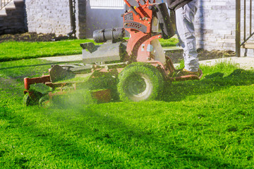 Fototapeta na wymiar Lawn mower cutting the grass gardening activity own home yard with lawn mower