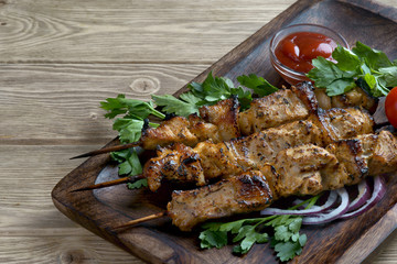 kebabs with greens and tomatoes on a wooden background