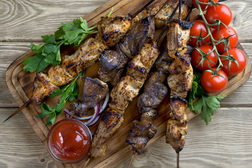 kebabs with greens and tomatoes on a wooden background