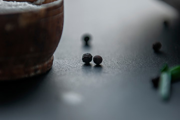Cooking spices - sea salt in a wooden container black pea pepper on the table. Selective front and back focus