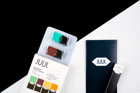 High end product shot of Juul vaper, e cigarette device along with flavoured juul vaping pods in package. Black and white diagonal flatlay background. Technology and modern concept.