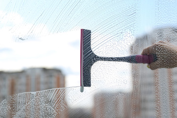 concept of window cleaning on urban  background with copy space. window squeegee cleans a soapy...