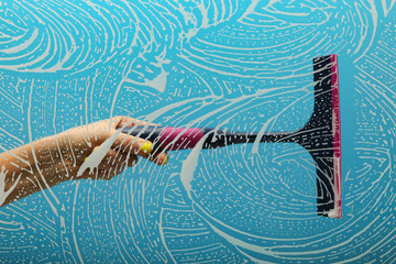concept of window cleaning on blue background with copy space. window squeegee cleans a soapy window
