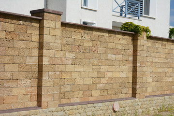 A close-up on brown oyster shell foamed brick, limestone brick fence with support pillars.