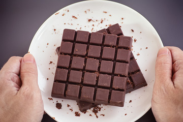 Man holding a white plate with homemade dark chocolate on it in his hands