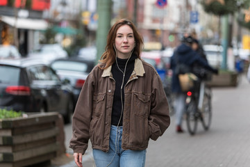 Young Woman Wearing Jeans and Brown Jacket on Sidewalk