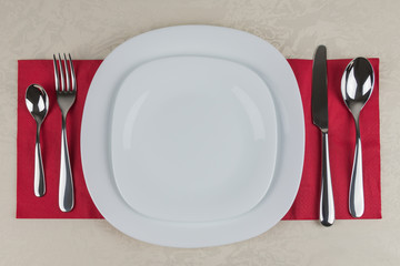 Plates and cutlery arranged on a red napkin.