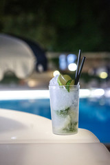 dettaglio di cocktail (moijto) isolato su sfondo piscina e locale notturno