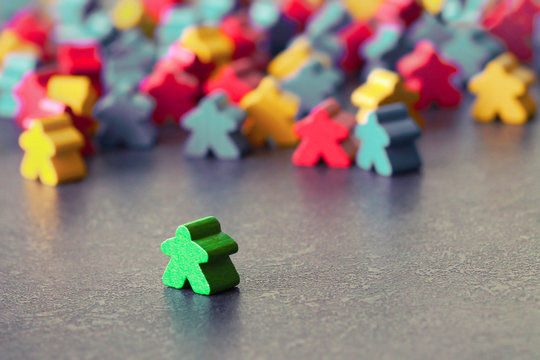 A single green figure of a man stands apart from a group of people of a different color. A symbol of exile from society and intolerance.