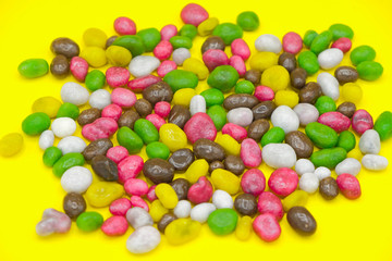 Multicolored bright candies scattered on a yellow surface. Candied raisins. Sweets of Ukraine.