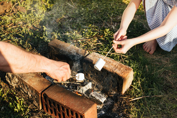 Fototapeta premium Marshmallows are fried on sticks on coals