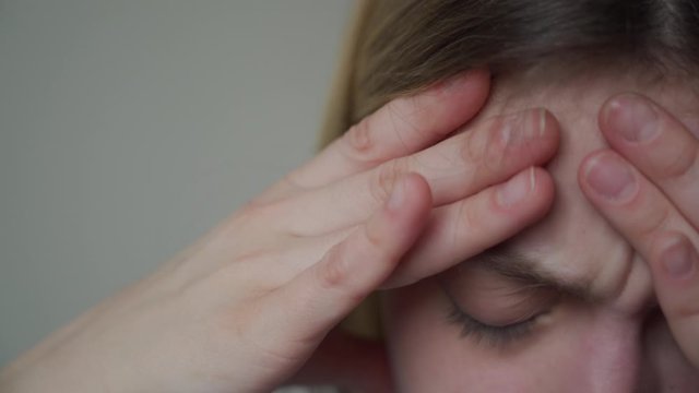 Painful face close-up. Finger massage of temples. The girl has a migraine, headache, malaise.