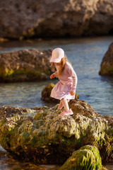 Happy pretty girl walks along the sea coast against the background of the sea, from behind a beautiful landscape