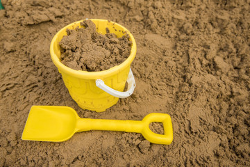 Yellow bucket and spade to make sandcastles out of golden sand