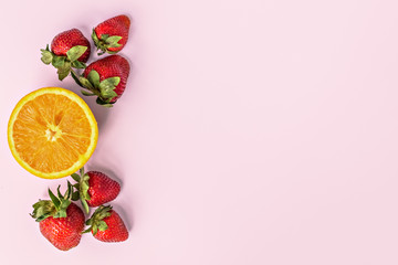 Ripe orange with fresh strawberries on a pink background