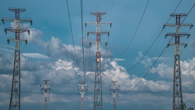 Electricity pylons cloud timelapse nature energy station electric poles the background of beautiful cloudy sky. Electricity station electric power plants and time lapse of high-voltage power lines.