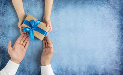 Happy father's day.Gift in the hands of daughter and father on a blue background.I love you,...