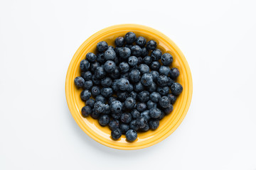 Blue berries in a yellow plate, top view