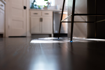 Floor view of grey wood floors in a modern kitchen with bar stool, white cabinets
