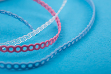close up.Orthodontic chain or elastic power chain.Multi-colored ligatures on a blue background for...