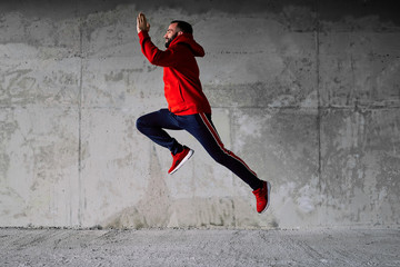 Young attractive bearded sportsman running under the bridge.