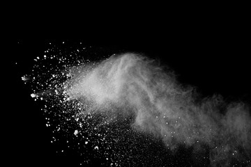 Freeze motion of white color powder exploding on black background.