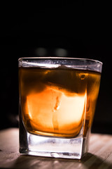 Glass of whiskey on wooden background close up