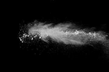 Freeze motion of white color powder exploding on black background.