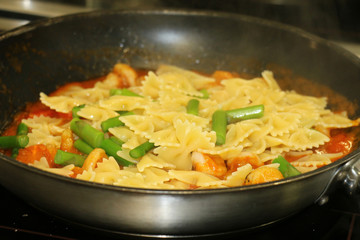 Cooking bow tie pasta in a chef's kitchen pan