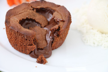 Chocolate dessert filled with hot chocolate cream on a plate with strawberries and cream ice cream