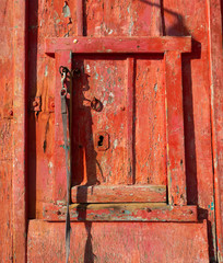 A rustic red window in a door at Klima Fishing Village - Milos Island, Greece