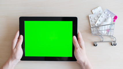 Online pharmacy concept. Woman holds a credit card and digital tablet with green screen. Online purchase of medicines with home delivery using the mobile application. Top view.