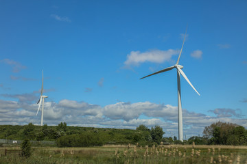 Windmill turbine on the field in UK with blue sky