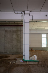 on  building site a drain pipe is led along a pillar