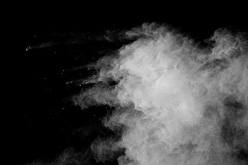 Freeze motion of white color powder exploding on black background.