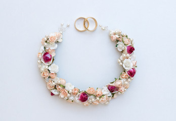 Gold wedding rings on a background of flowers. Flowers in the form of a garland. Perfect for wedding invitations and greeting cards.
